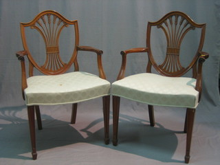 A pair of mahogany shield back open arm carver chairs with upholstered seats, raised on square tapering supports ending in spade feet