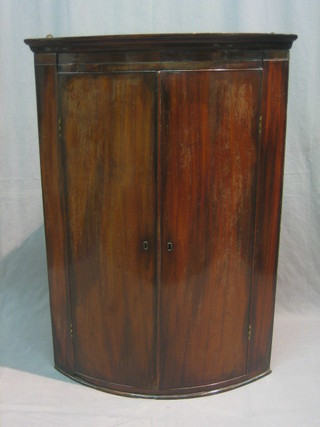 A 19th Century mahogany bow front hanging corner cabinet fitted shelves enclosed by a panelled door 29"