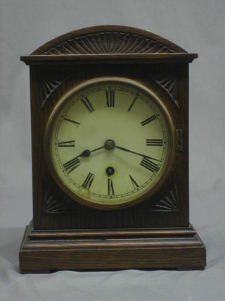 An Edwardian mantel clock with paper dial and Roman numerals contained in an arch shaped oak case