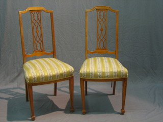A set of 4 Edwardian inlaid satinwood bar back dining chairs with pierced splat backs and upholstered seats, raised on square tapering supports (2 with broken backs)
