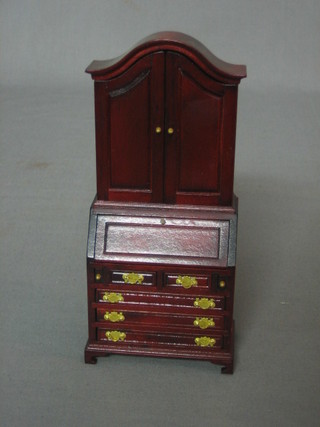 A dolls house mahogany bureau bookcase, the upper section enclosed by a panelled door the fall front revealing a well fitted interior above 2 short and 3 long drawers, raised on ogee bracket feet 3" (1 back foot f)
