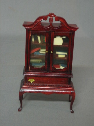 A dolls house Georgian style mahogany cabinet on stand enclosed by glazed panelled door, the base fitted a drawer, raised on cabriole supports 3", together with contents of dolls house books
