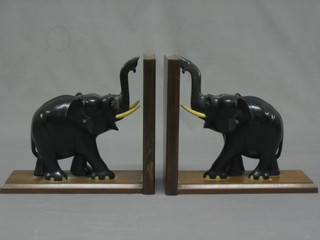 A pair of ebony book ends in the form of standing elephants with ivory tusks 11"