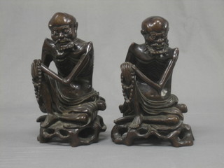A pair of Eastern carved root wood figures of seated sages, with ivory teeth and eyes 12"
