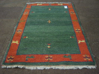 A contemporary green ground Eastern rug with tan border decorated animals 66" x 98"