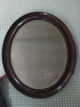 An oval bevelled plate wall mirror contained in a mahogany frame 28"