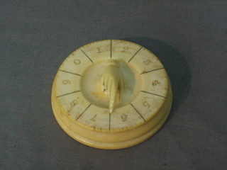 A circular carved ivory card scorer in the form of hand