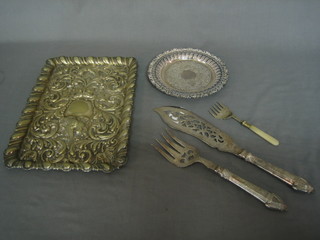 A rectangular embossed silver plated dressing table tray, a small silver plated salver, a pair of silver plated fish servers and a sardine fork