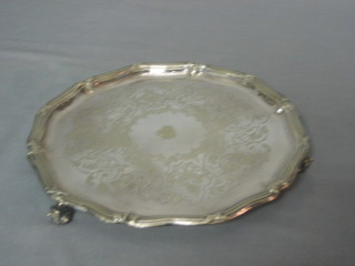 A silver plated salver with bracketed border and engraved armorial decoration, raised on scroll feet 10"