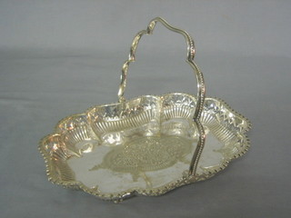 A shaped silver plated cake basket with swing handle raised on claw and ball feet