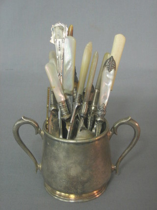 A silver plated twin handled hotelware sugar bowl containing a small collection of flatware