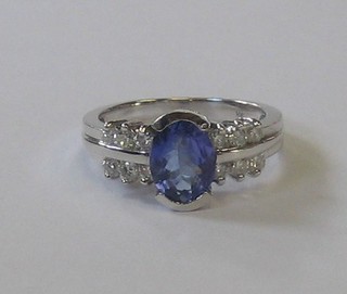 A 14ct white gold dress ring set an oval cut tanzanite supported by 6 diamonds to the shoulders