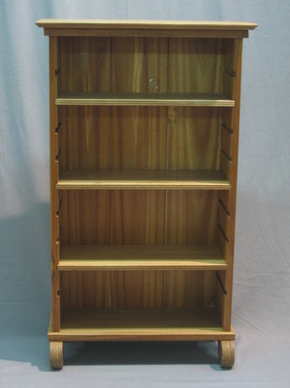A bleached mahogany finished bookcase fitted adjustable shelves raised on scroll supports 22"