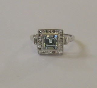 A lady's 18ct white gold dress ring set a square cut aquamarine supported by numerous diamonds