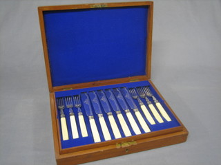 A canteen containing 6 silver plated fruit knives and forks with mother of pearl handles and 6 fish knives and forks with bone handles, contained in a walnut canteen box