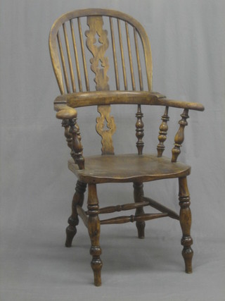A 19th Century elm stick and wheel back Windsor carver chair with broad arms, raised on turned supports