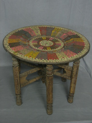 A circular Benares brass table, raised on a carved folding stand 23"