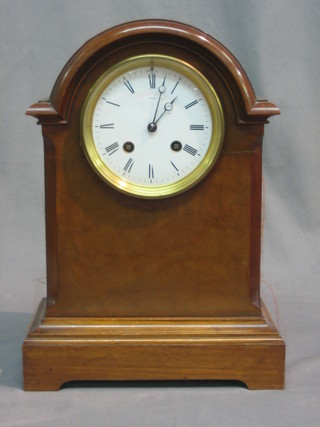 A French 8 day striking mantel clock with enamelled dial and Roman numerals contained in an arch shaped walnut case