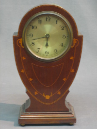 An Art Nouveau mantel clock with silvered dial and Arabic numerals contained in a shaped inlaid mahogany case