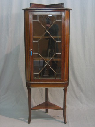 An Edwardian inlaid mahogany corner cabinet with raised back, the interior fitted shelves enclosed by an astragal glazed panelled door, raised on square tapering supports 22"
