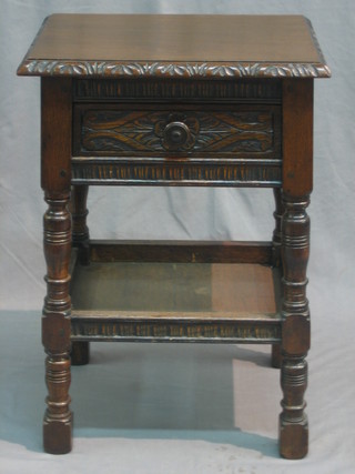 A carved oak 2 tier occasional table fitted a drawer raised on turned and block supports 17"
