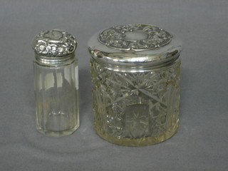 A cylindrical cut glass pin jar with embossed silver lid and a cylindrical dressing table jar with embossed silver lid (2)