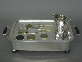 A rectangular silver plated twin handled hot plate, a silver plated cream jug, a silver plated jam spoon and serving fork with mother of pearl handle, a cartwheel penny, a George V 1925 crown and a Churchill crown