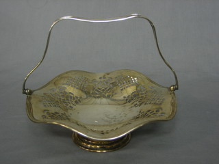 A circular pierced silver plated cake basket with swing handle