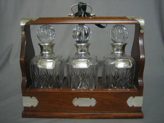 A modern silver and mahogany 3 bottle tantalus, containing 3 cut glass decanters with silver collars and decanter labels - gin, whisky and brandy