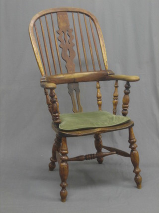 An 18th/19th Century Windsor stick back carver chair with broad arms, raised on turned supports united by an H framed stretcher