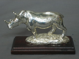 A silvered model of a Rhino, raised on a wooden base 6"
