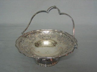 A circular silver plated cake basket with swing handle