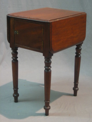 A Victorian mahogany drop flap work table enclosed by panelled doors, raised on turned supports 19"