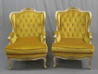 A pair of Spanish carved light wood winged armchairs upholstered in yellow material, raised on cabriole supports by Mariana Garcia J.L. of Spain