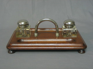 An oak standish set 2 cut glass inkwells with silver plated hinged lids, the base fitted 2 pen recepticals, raised on bun feet 12"