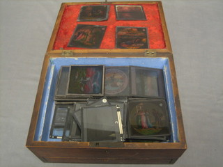 A Victorian mahogany trinket box with hinged lid containing a collection of various coloured Magic Lantern slides