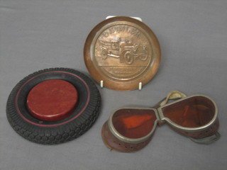 A circular embossed copper ashtray marked Daimler Coventry, London, Manchester, Nottingham and Bristol 3", an Indian rubber tyre ashtray and a pair of orange tinted goggles