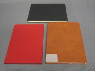 An orange stock book of World stamps, a brown stock book of World stamps and a black stock book of World stamps
