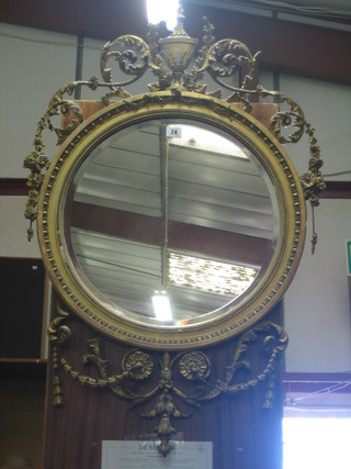 A circular bevelled plate wall mirror contained in a gilt plaster frame surmounted by a lidded urn 19"