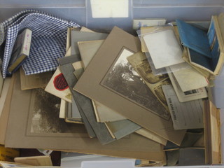 A transparent plastic crate containing a collection of photographs etc
