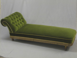 An Edwardian oak framed chaise longue, upholstered in green material, raised on bun feet 68"