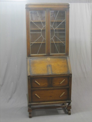 An Art Deco oak bureau bookcase the upper section fitted adjustable shelves enclosed by lead glazed panelled doors, the base fitted a fall front revealing a fitted interior above 2 long drawers, raised on bulbous supports 30"