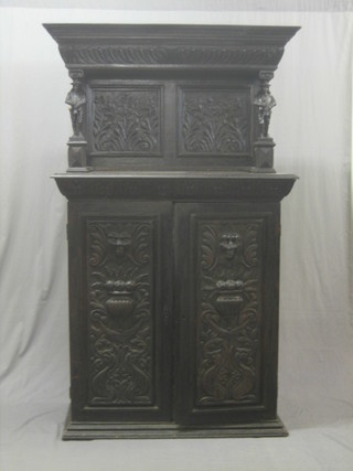 A Victorian heavily carved ebonised oak cabinet with raised back supported by 2 figures of minstrels, the base fitted a cupboard with shelf enclosed by carved panelled doors, raised on a platform base 42"