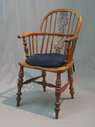 An 18th/19th Century yew and elm Windsor stick back kitchen carver chair with pierced slat back, raised on turned supports united by an H framed stretcher