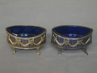 A pair of pierced oval Georgian style silver salts, raised on panel feet, Chester 1909, 2 ozs, complete with blue glass liners