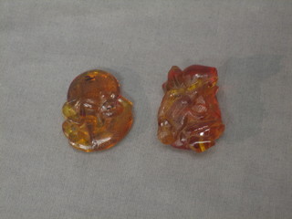 A carved amber figure in the form of a monkey with a pearl 1 1/2" and 1 other in the form of a seated monkey 1"