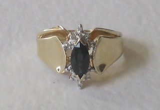 A yellow gold dress ring set a marquise cut sapphire supported by diamonds