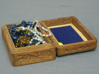 An Eastern rectangular carved hardwood box containing a collection of various beads