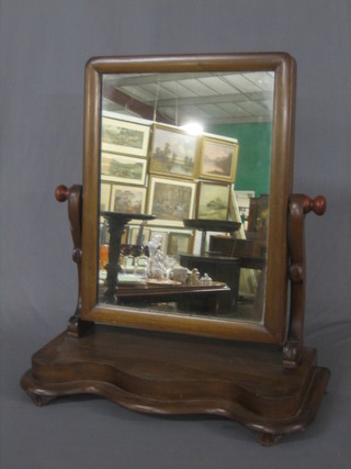 A Victorian mahogany rectangular plate dressing table mirror contained in a mahogany swing frame, raised on a shaped base 19"