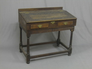 An antique carved oak writing slope with hinged lid, the interior fitted 2 drawers, raised on turned and block supports 35"
